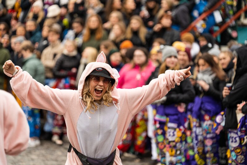 Opiskelija juhlii naamiaisasussa, taustalla iso joukko opiskelijoita.
