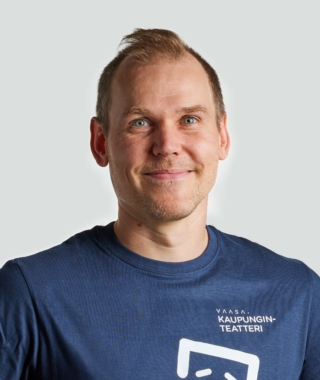 Henkilö katsoo hymyillen kameraan.